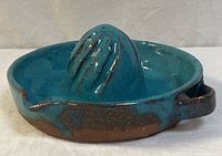 Full view of blue glazed stoneware juicer showing handle and spout