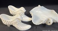 Full view of two hobnail milk glass shoes and crimped-edge handled dish
