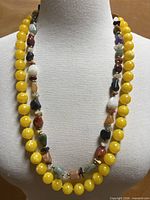 Both necklaces displayed on bust—yellow bead strand outer, mixed stone inner