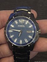 Front view showing blue dial, crystal indices, date window, bezel and bracelet