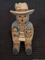 Front view of seated storyteller pottery figure with two children