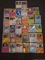 Full grid of approximately 32 holographic Pokémon cards laid out on carpet