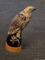 Full view of carved wooden bird figurine on stand