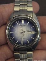 Front view showing blue gradient dial, baton markers, day-date window