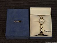 Watch in open presentation box beside blue Seiko outer box