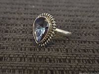 Front view showing pear-shaped faceted stone and rope bezel