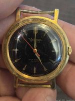 Front view showing gold-tone case, black dial, red seconds hand, Waltham logo