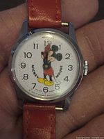 Close view of watch dial showing Mickey Mouse graphic, brand name, numerals, and overall face condition