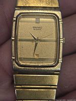 Close-up front view of gold-tone Seiko quartz watch face showing rectangular case, dial, hands, and date window