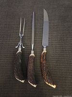 Full view of three-piece carving set on dark cloth