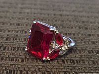 Oblique view showing large red emerald-cut stone and side accents