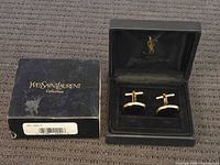 Cufflinks in open presentation case beside outer box
