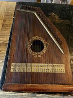Front view of chord zither showing strings, rosette, scale chart and tuning pins