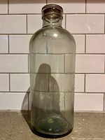 Front view of tall clear glass jar with stopper