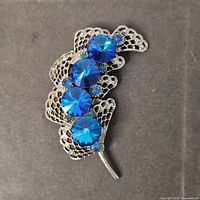 Front view showing blue rivoli stones and filigree leaf design