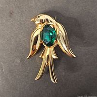 Front view showing gold-tone bird brooch and green rhinestone