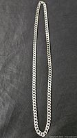 Full view of sterling silver curb link chain necklace laid flat