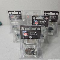 Group of five unopened NFL shot glasses in packaging