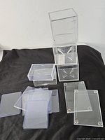 Stack of clear storage boxes, hinged box, screw-down cases and snap holders on black cloth