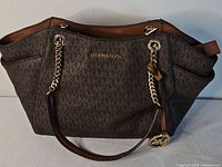 Front view of Michael Kors Jet Set brown monogram tote showing logo and chain-link straps