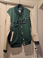 Front view showing green body, white leather sleeves, chest embroidery, snap closure