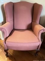 Front view of one pink wingback chair with wood cabriole legs