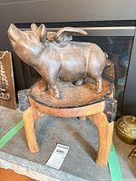 Iron pig figurine on wooden stool front view