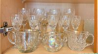 Cut-glass stemware and small pitchers on cabinet shelf