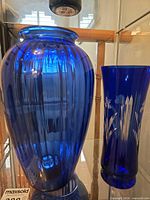 Two blue glass vases on display shelf