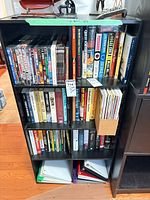 front view of black laminate bookcase loaded with books and DVDs (contents not included)
