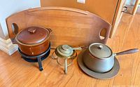 All items together: wood tray, brown chafing dish on stand, brass burner, grey fondue pot on plate
