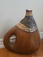 Full left-angle view of canteen-shaped vase showing handle cut-out and metal scale accents