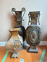 Front view of three metal vases showing shapes and designs