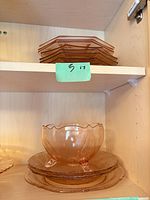 Stack of octagonal plates on upper shelf, large footed bowl and round plates on lower shelf