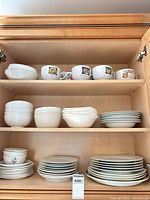 Full cabinet view showing all dinnerware stacks and soup mugs