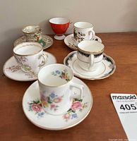 Six assorted teacups with saucers arranged on wooden surface