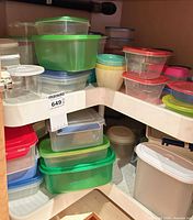 Cabinet shelf with multiple clear and colored plastic containers and lids