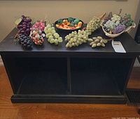 Cabinet with grape clusters and fruit on top