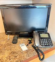 Front view of Hitachi TV, Panasonic phone, remote and cables