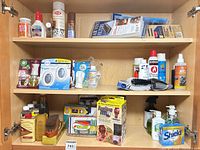 Three-shelf cabinet showing variety of air fresheners, filters, soaps, brush, sprays and boxes