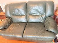 Front view of dark green leather loveseat showing overall appearance