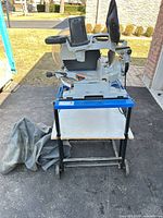 Full view of Mastercraft table saw on blue wheeled stand with cover on ground