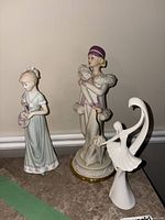 Three porcelain figurines grouped together on tabletop