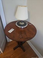 Round wooden side table with lamp on top