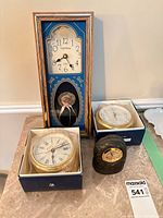 Group shot showing wall clock, two boxed brass instruments, black desk clock