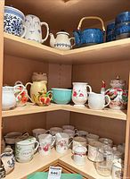 Middle and bottom shelves with creamers, mugs, glass teapots