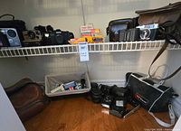 Overall view of shelf with cameras, lenses, film packs, cases and accessories