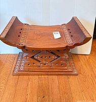 Front angle of carved wooden stool showing seat and base