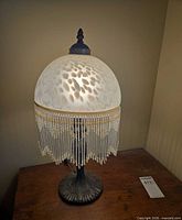 Lamp illuminated to show working condition, full view of shade, beads, and base