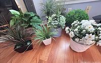 Group view of six artificial potted plants on floor